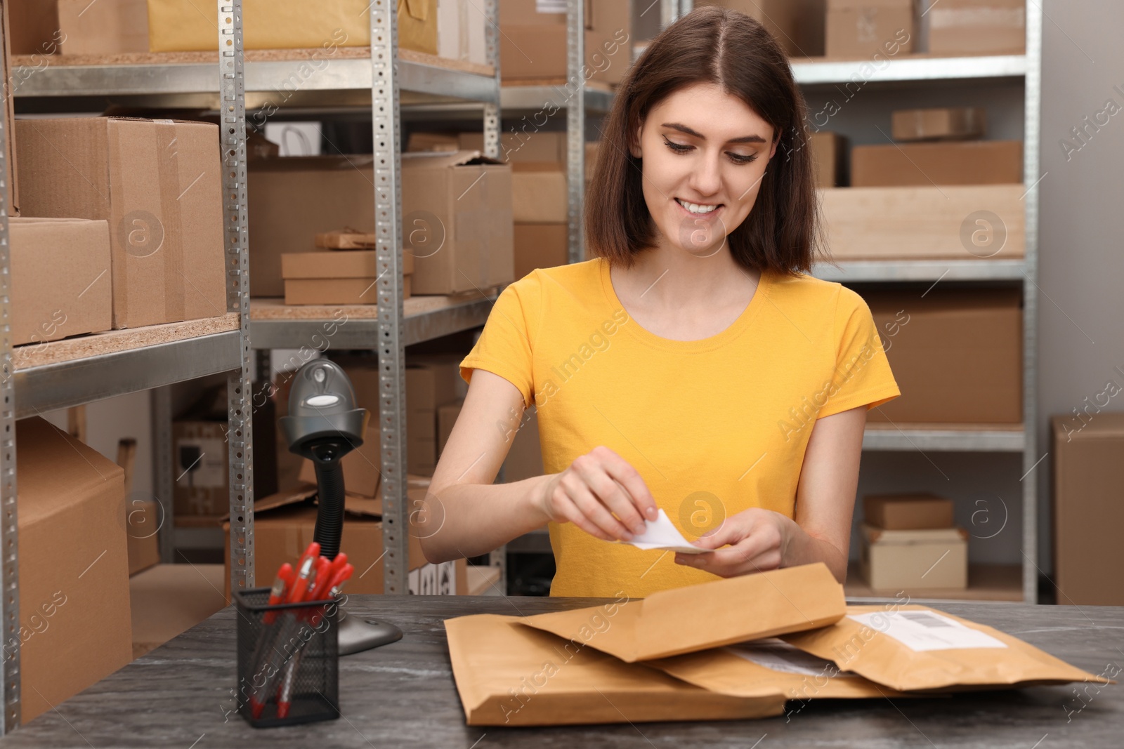 Photo of Post office worker sticking barcode on parcel at counter indoors