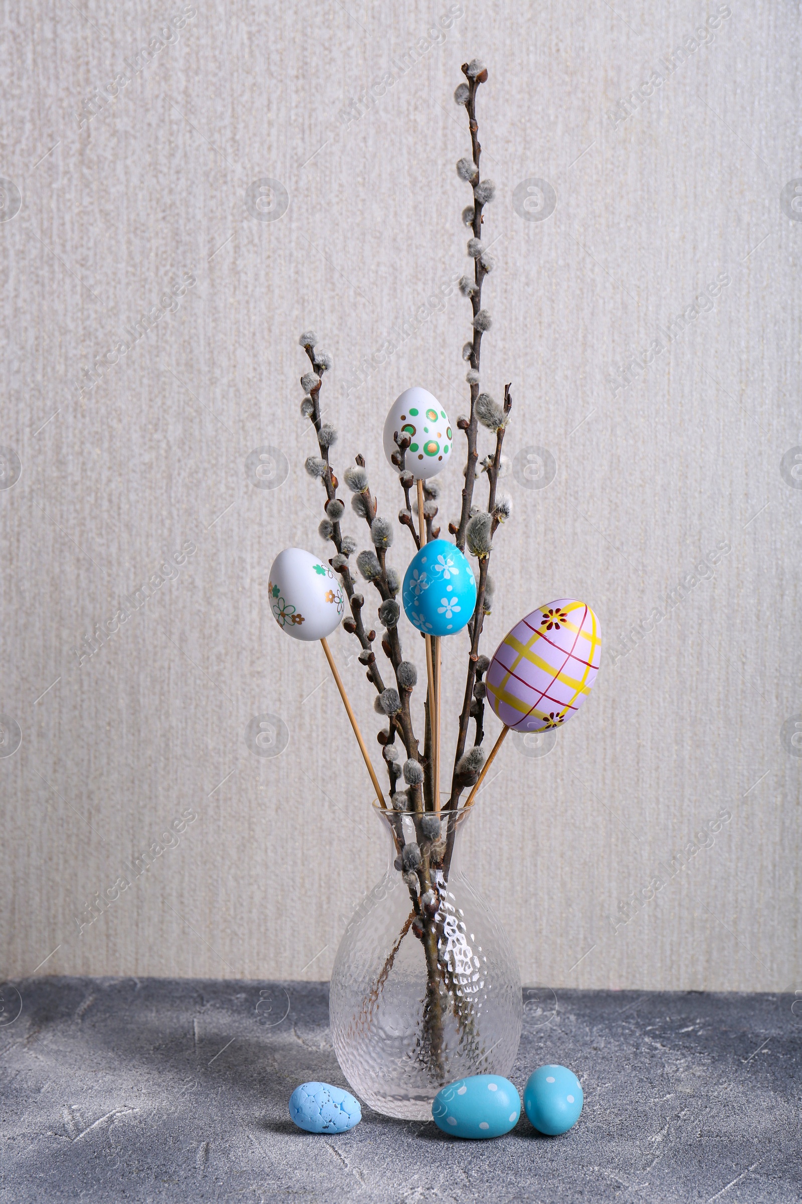 Photo of Beautiful willow branches with painted eggs on light grey table. Easter decor