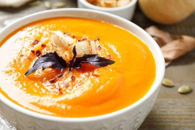 Delicious pumpkin soup in bowl on table, closeup