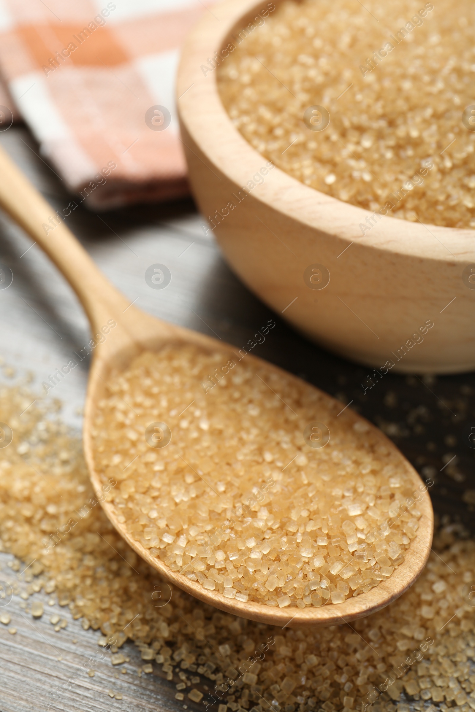 Photo of Brown sugar in bowl and spoon on wooden table, closeup