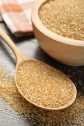 Photo of Brown sugar in bowl and spoon on wooden table, closeup