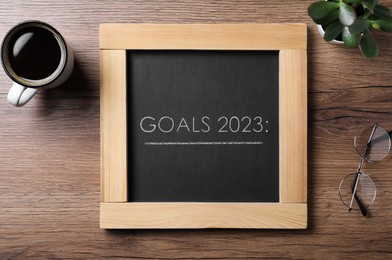 Image of Blackboard with phrase GOALS 2023 on wooden background, flat lay