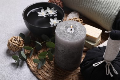 Beautiful composition with burning candle and spa products on light grey table