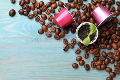 Coffee capsules, seedling and beans on light blue wooden table, flat lay. Space for text