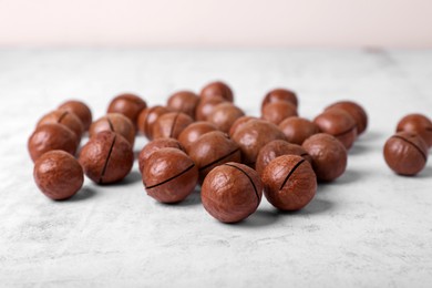 Delicious organic Macadamia nuts on white textured table, closeup