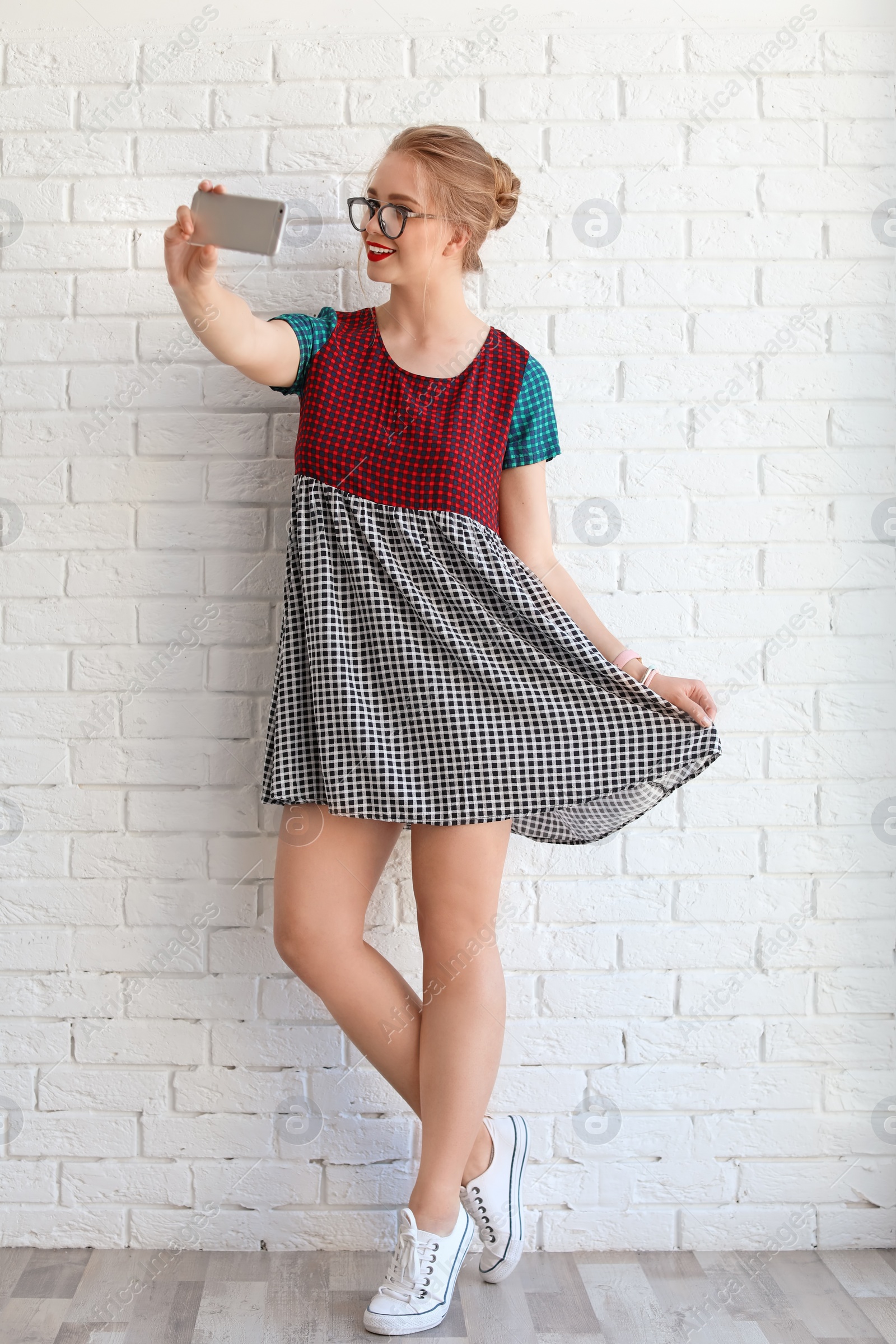 Photo of Attractive young woman taking selfie near brick wall