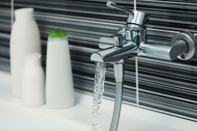 Photo of Water flowing from bath tap installed on black and white wall