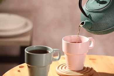Photo of Pouring aromatic tea into cup at wooden table