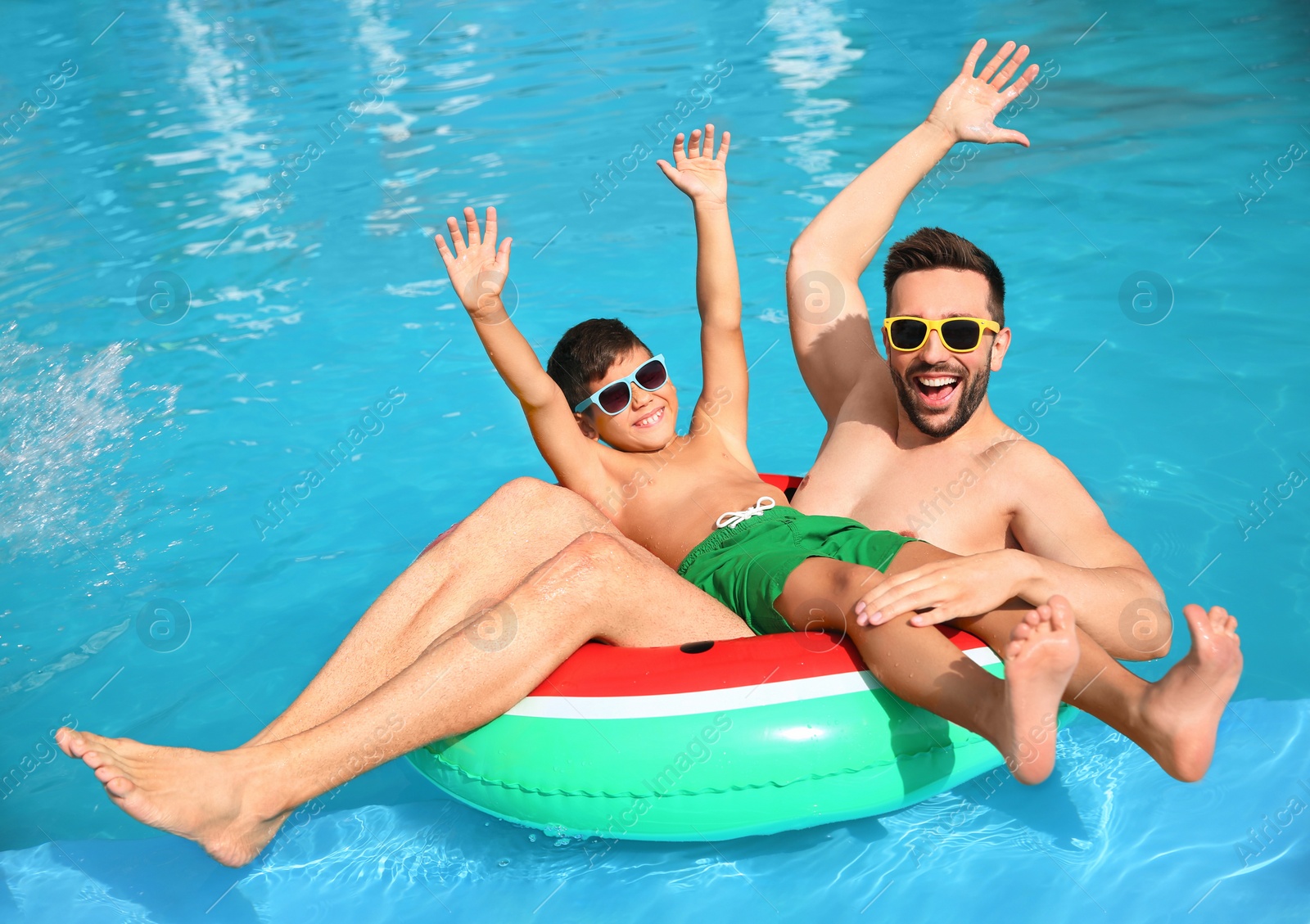 Photo of Father and son having fun in swimming pool. Family vacation