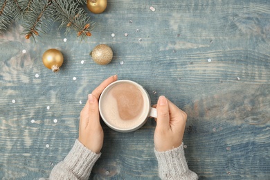 Photo of Woman with delicious hot cocoa drink at table, top view
