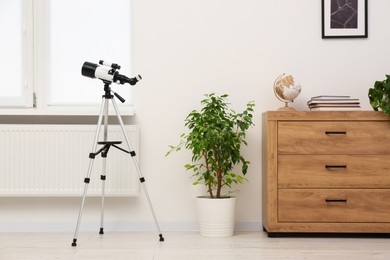 Photo of Tripod with modern telescope in stylish room