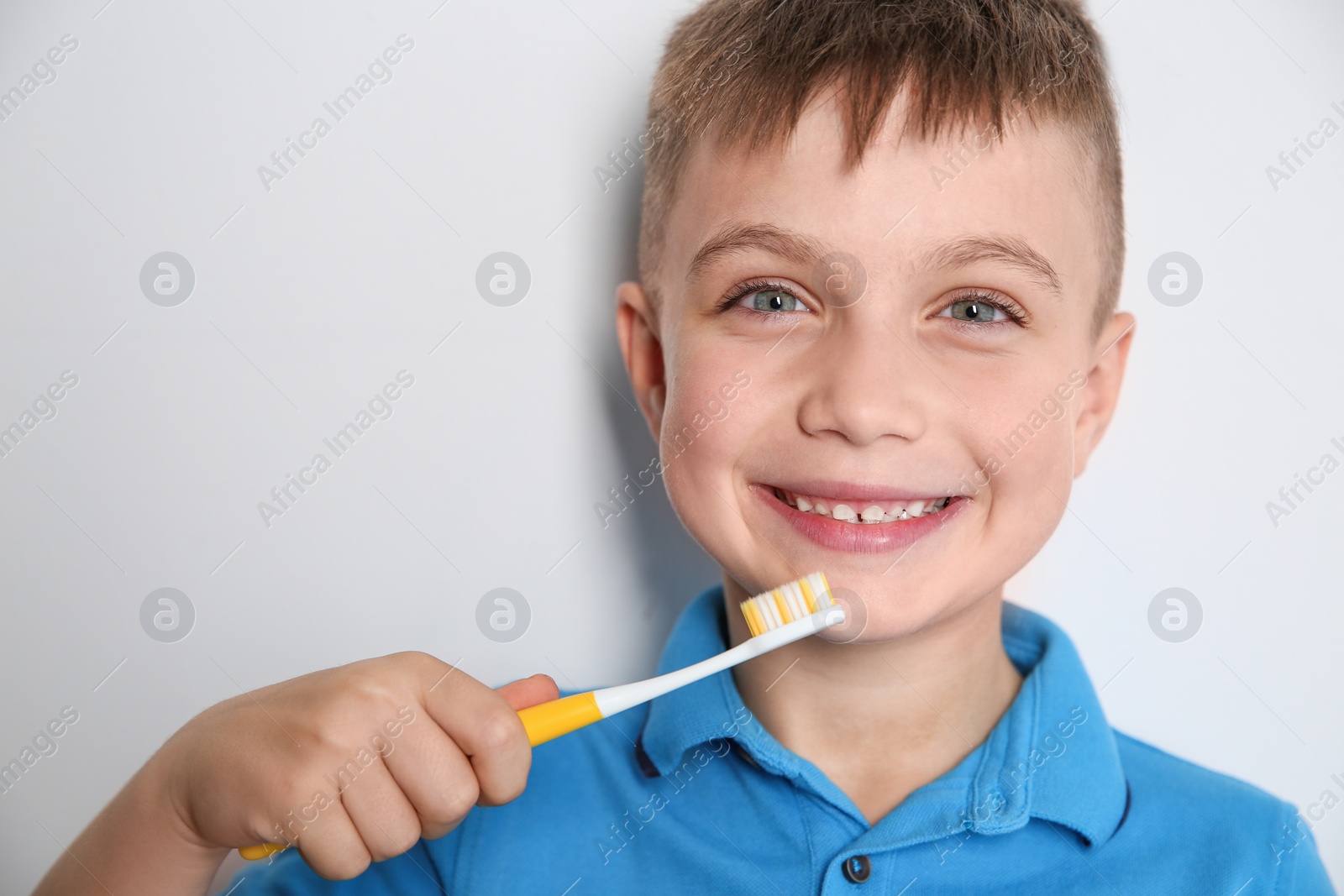 Photo of Portrait of little boy with toothbrush on light background. Space for text