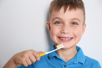 Portrait of little boy with toothbrush on light background. Space for text