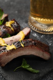 Photo of Delicious grilled ribs on dark grey textured table, closeup