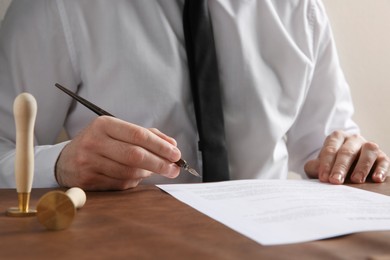 Photo of Male notary signing document at table, closeup