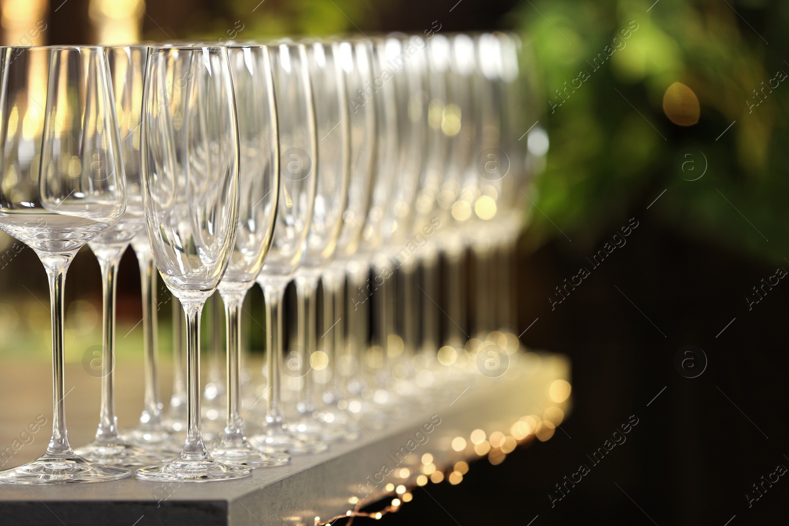 Photo of Set of empty glasses on grey table against blurred background