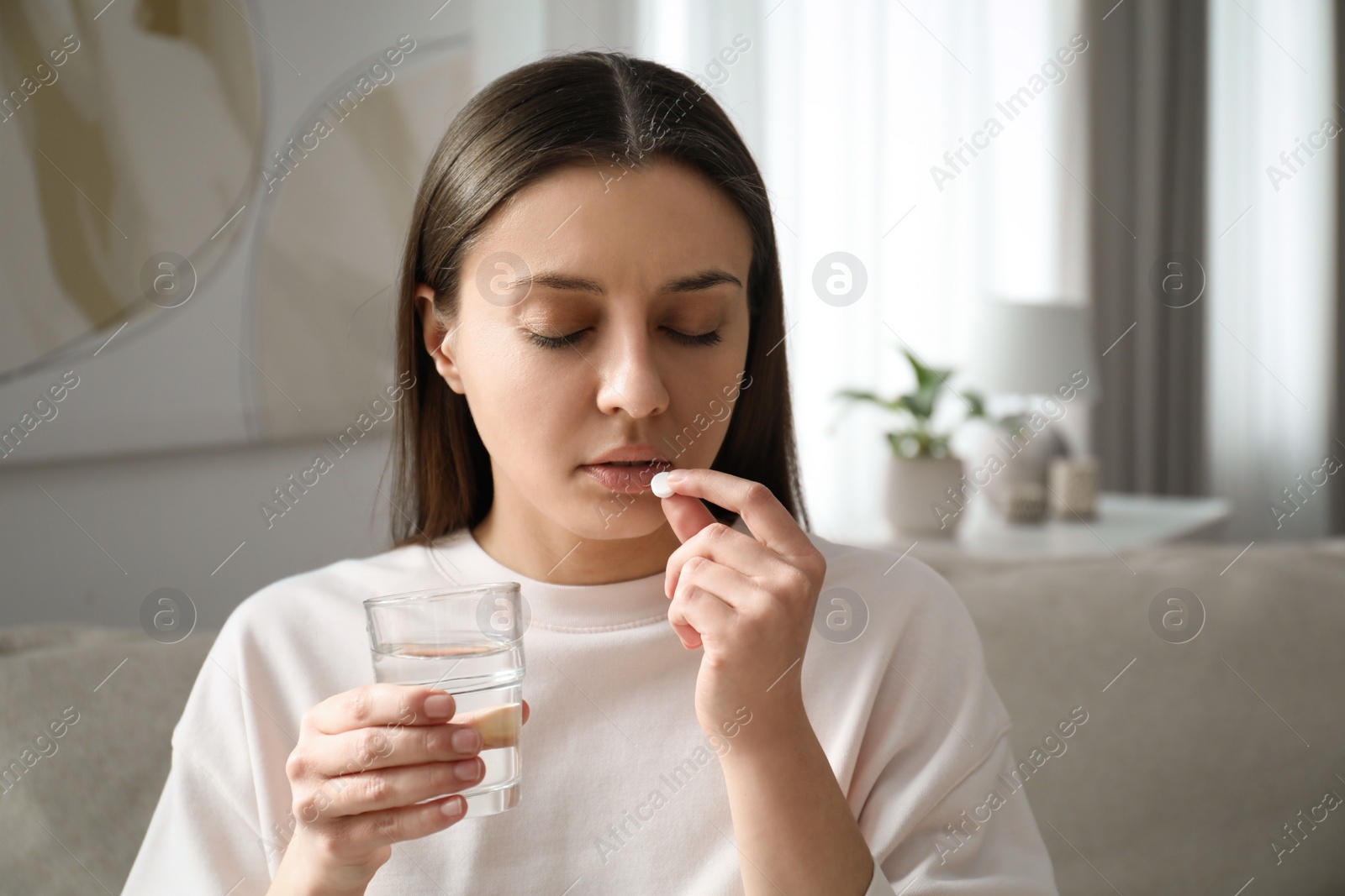 Photo of Young woman taking abortion pill at home