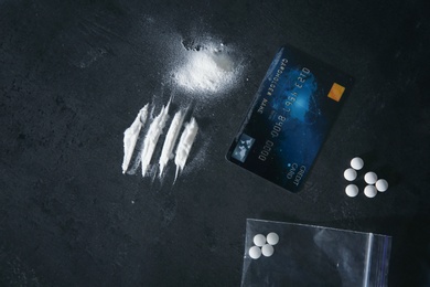 Photo of Different drugs and credit card on dark background, flat lay