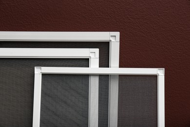 Photo of Set of window screens near brown wall, closeup