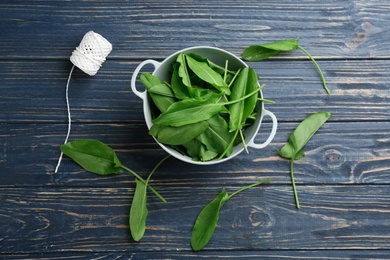 Photo of Fresh green sorrel leaves and thread on blue wooden table, flat lay