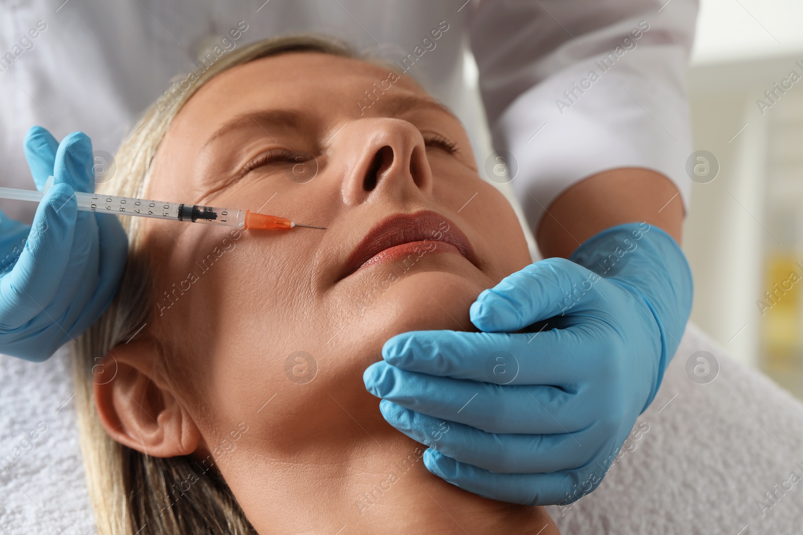 Photo of Doctor giving facial injection to senior woman in clinic, closeup. Cosmetic surgery