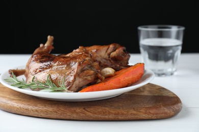 Photo of Tasty cooked rabbit meat with rosemary, garlic and carrot on white table, closeup