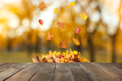 Image of Wooden surface and falling autumn leaves outdoors 