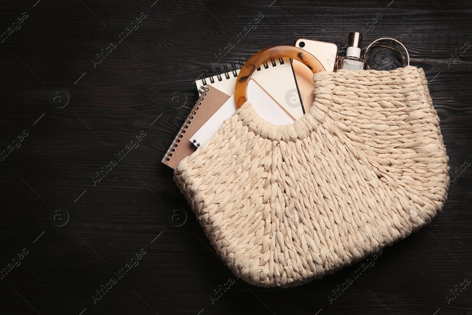 Photo of Stylish woman's bag with smartphone and accessories on black wooden background, top view