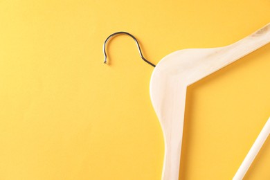 Photo of One wooden hanger on yellow background, top view. Space for text