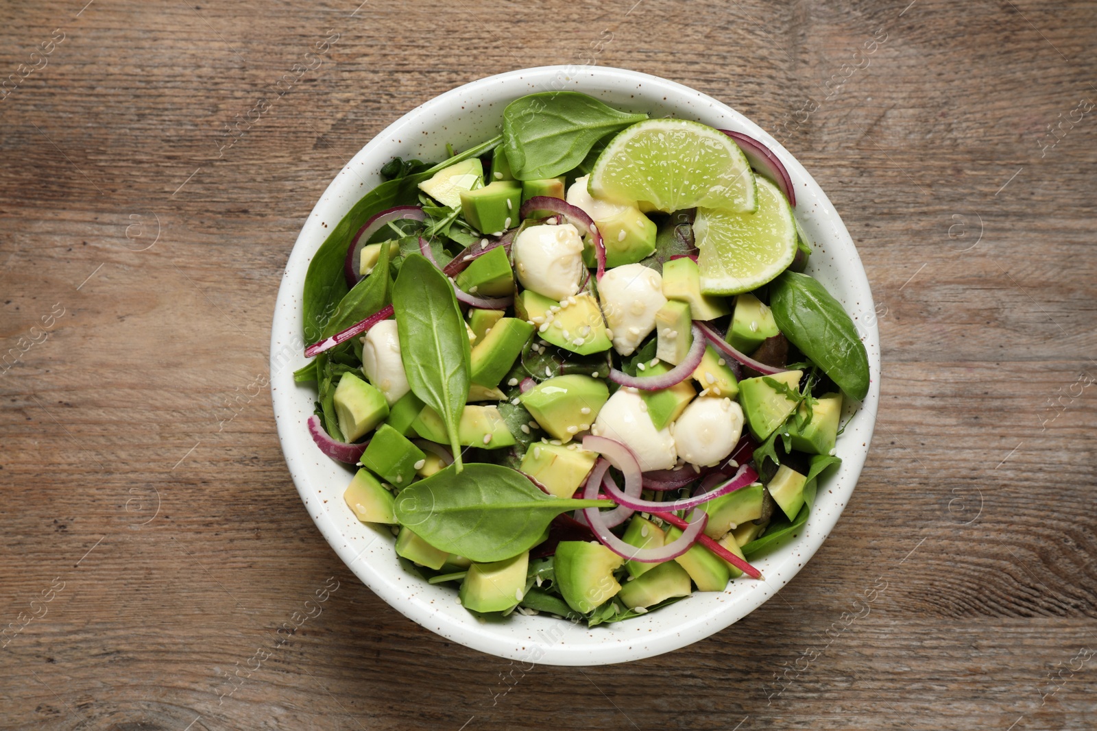 Photo of Delicious avocado salad with mozzarella on wooden table, top view