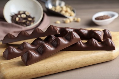 Photo of Board with tasty chocolate bars on wooden table, closeup