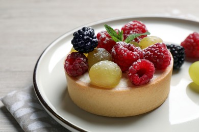 Photo of Delicious tartlet with berries on light wooden table, closeup