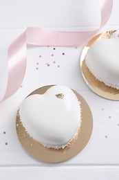 Photo of St. Valentine's Day. Delicious heart shaped cakes and confetti on white wooden table, flat lay
