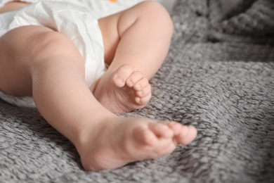 Photo of Little baby with cute feet on soft blanket, closeup