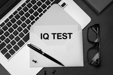 Photo of Paper with words IQ Test in envelope, glasses and laptop on black table, flat lay