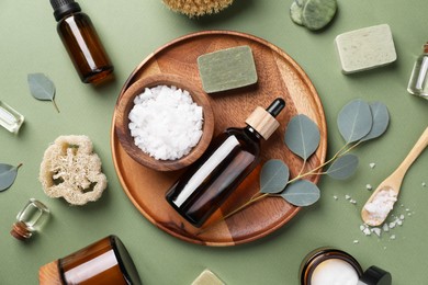 Flat lay composition with different spa products and eucalyptus branches on olive background