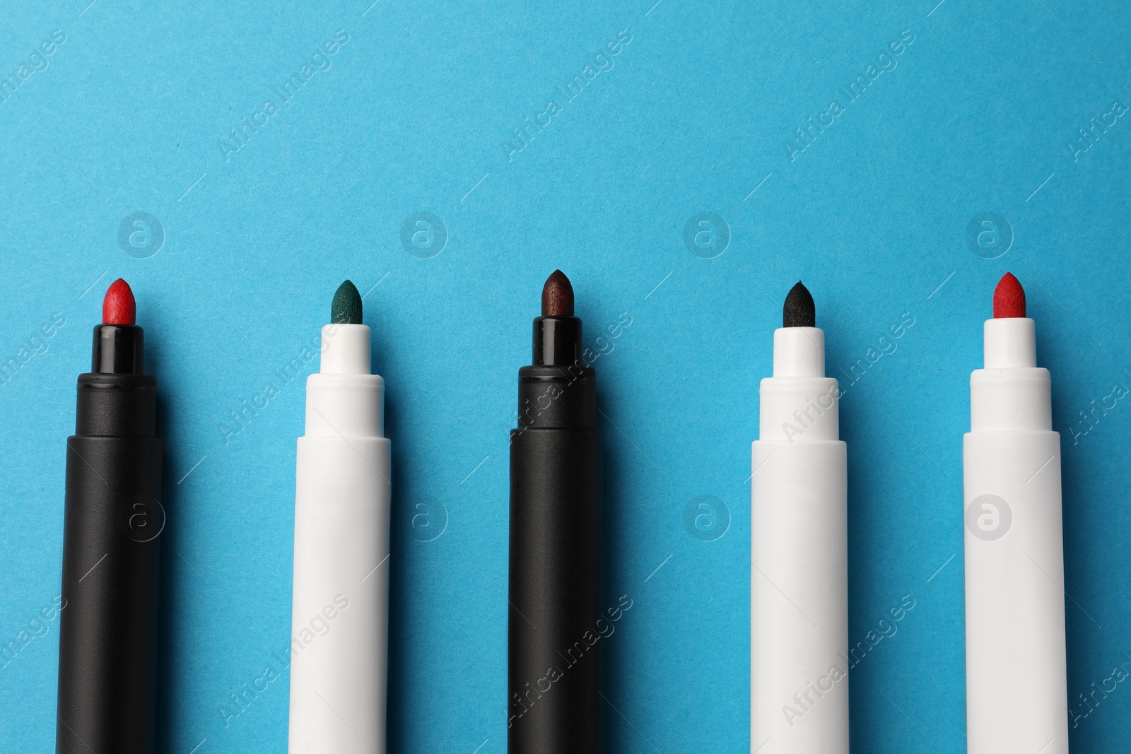 Photo of Bright color markers on light blue background, flat lay. Space for text