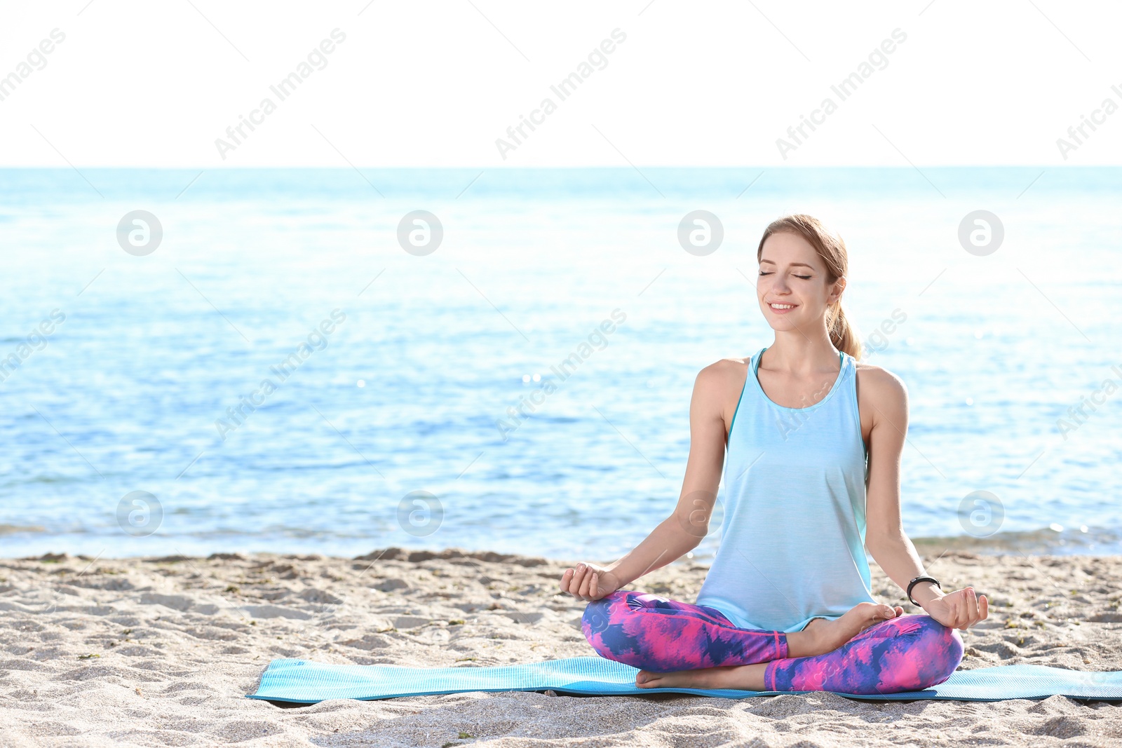 Photo of Young woman doing yoga exercises on beach in morning