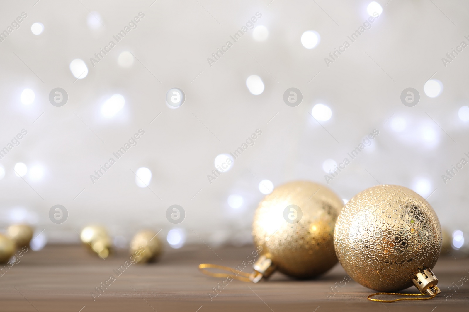 Photo of Beautiful Christmas balls on table against blurred festive lights. Space for text