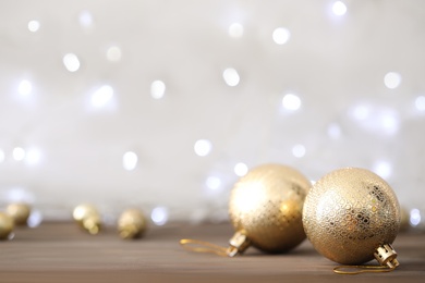 Beautiful Christmas balls on table against blurred festive lights. Space for text