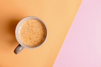 Cup of aromatic hot coffee on color background, top view