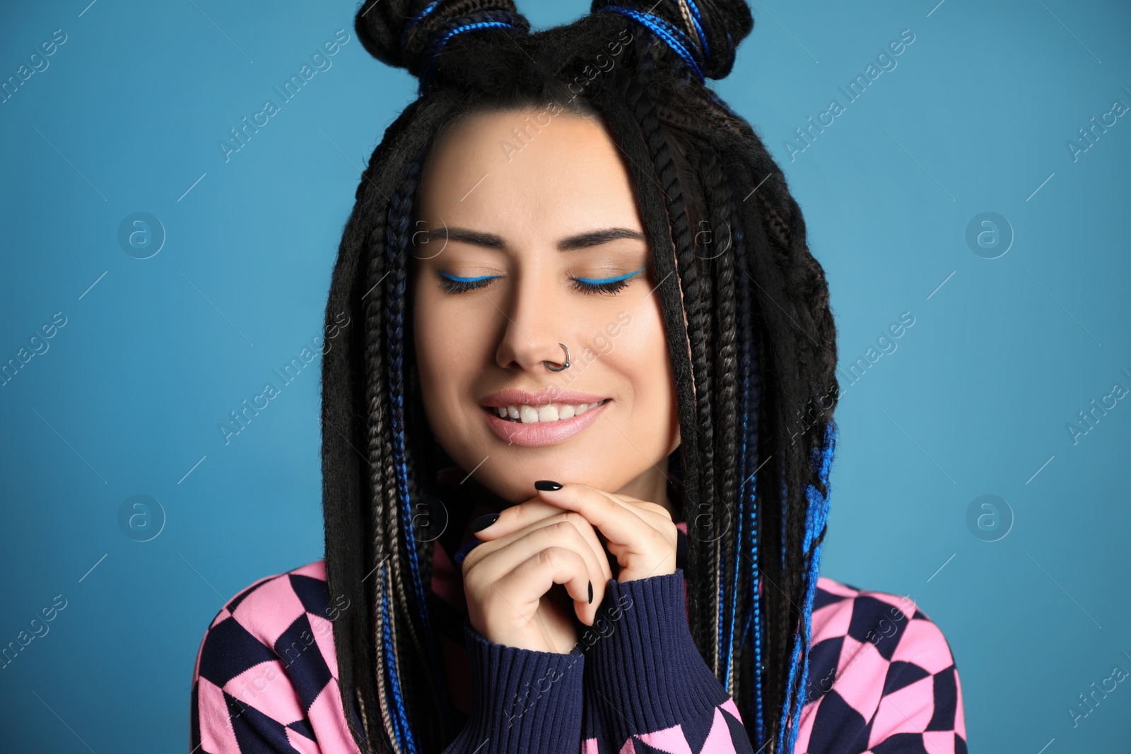 Photo of Beautiful young woman with nose piercing and dreadlocks on light blue background