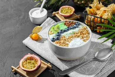 Photo of Tasty smoothie bowl with fresh kiwi fruit, blueberries and oatmeal served on black table