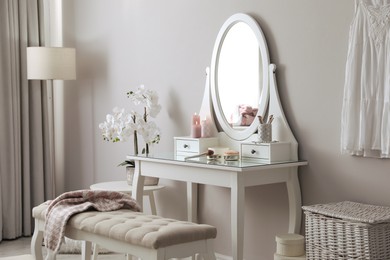 Wooden dressing table with decorative elements and makeup products in room. Interior design