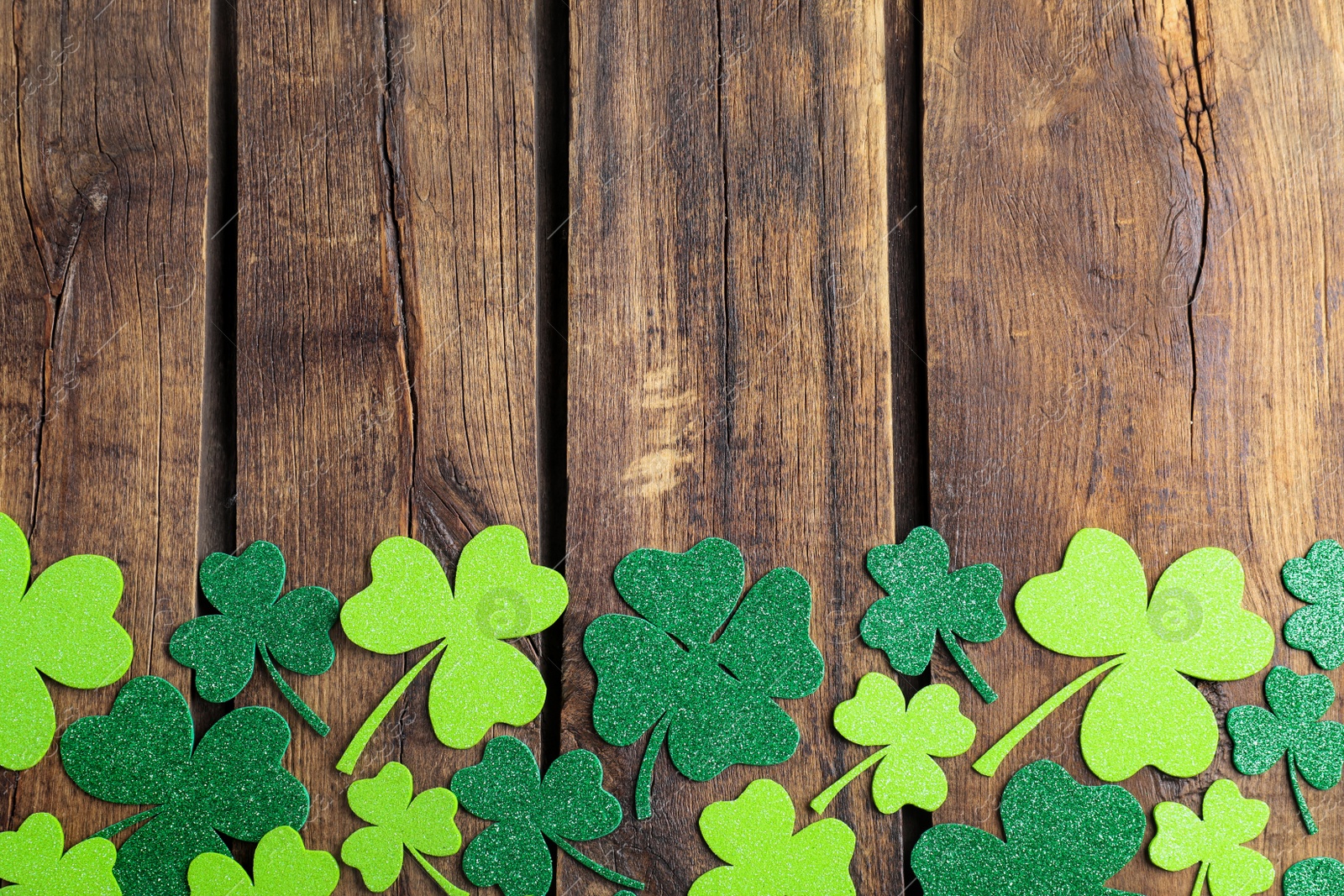 Photo of Flat lay composition with clover leaves on wooden table, space for text. St. Patrick's Day celebration