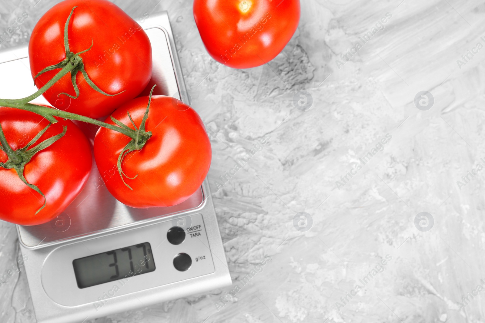 Photo of Kitchen scale with tomatoes on grey textured table, top view. Space for text