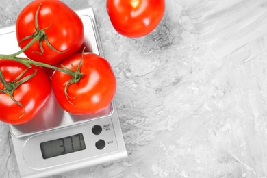 Kitchen scale with tomatoes on grey textured table, top view. Space for text