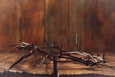 Crown of thorns on wooden table, space for text. Easter attribute