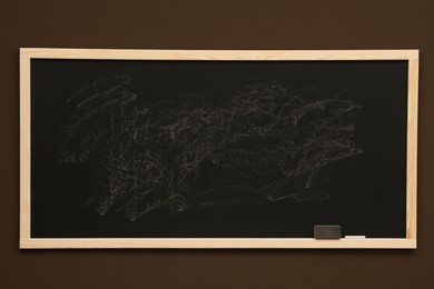Photo of Dirty black chalkboard hanging on brown wall