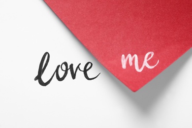 Photo of Phrase Love Me written on white and red paper